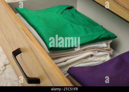Stacks of different folded shirts in drawer, closeup. Organizing clothes Stock Photo