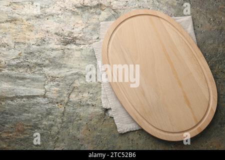 Wooden cutting board and napkin on textured table, top view. Space for text Stock Photo