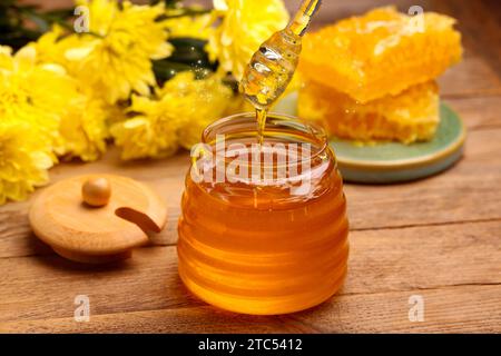 Natural honey in glass jar and dipper on wooden table under sunlight Stock Photo