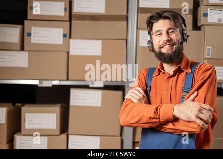 Male worker wearing headset in logistics distribution warehouse looking at camera and smiling Stock Photo