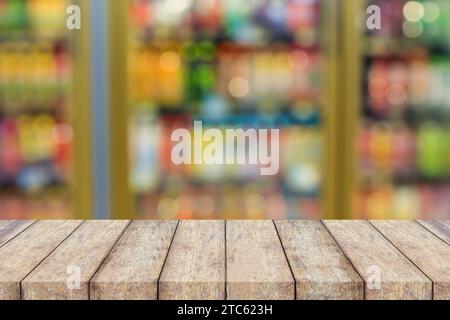 wood table top over convenience store refrigerator shelves blurred background Stock Photo