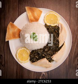 Lebanese recipe Mouloukhia , Melokhiyah, corete leaf, coriander, rice, chicken, grilled pita Stock Photo