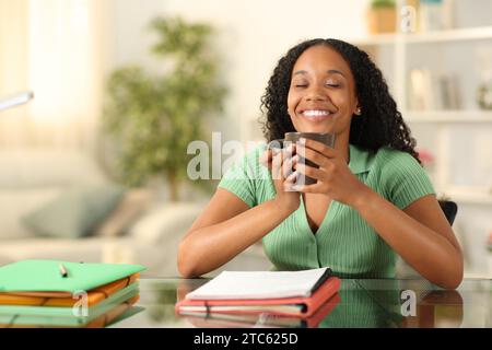Happy black student having a coffee break at home Stock Photo