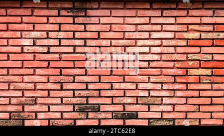 A close-up of a brick wall with signs of wear and tear, with chipping paint and faded colors Stock Photo