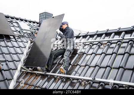 Solar Panel Technician Installing Photovoltaic System on Residential Rooftop Stock Photo