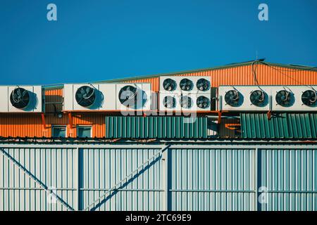 Industrial warehouse with heat pumps external units mounted on building roof with sky as copy space Stock Photo