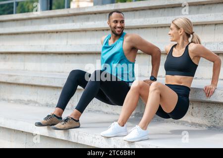 Sporty woman and man doing reverse push ups outdoors. Stock Photo