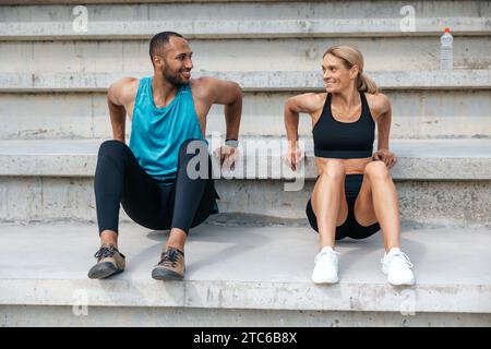 Sporty woman and man doing reverse push ups outdoors. Stock Photo