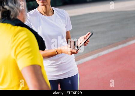 trainer showing workout on tablet to a senior man Stock Photo