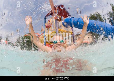 A boy  playing under a fountain in a pool on July 7, 2007 in Fort Collins, Colorado. Stock Photo