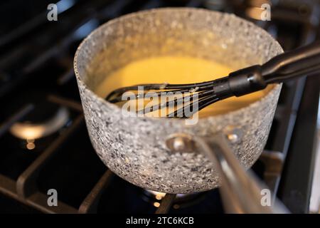 turkey gravy and a whisk in a pot on a stove Stock Photo