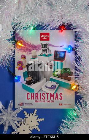 A 2017 Argos Christmas catalogue (gift guide). Photographed on a neutral background with coloured Christmas lights, decorations and luxury tinsel. Stock Photo