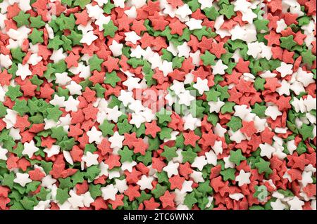 Star shaped sugar sprinkles. Background of green, red and white confetti candy, confectionery made of sugar and rice. Stock Photo