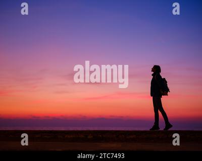 Woman tourist against colorful sunset sky. Travel, tourism concept. Active lifestyle. Stock Photo