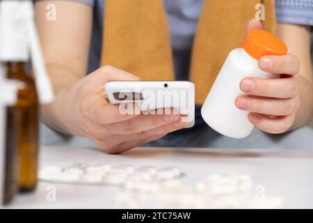 Woman reading instructions for the use of medication on the Internet using a smartphone. Online appointment with a doctor. Stock Photo