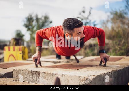 Young man is exercising outdoor. He is doing push-ups. Stock Photo