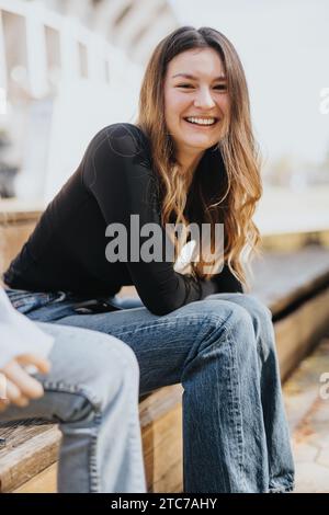 Female university student smiling while taking a break from studying with her friends outside in a beautiful park on a sunny day. Stock Photo