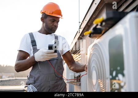 Busy repairman checking voltage level in air conditioner Stock Photo
