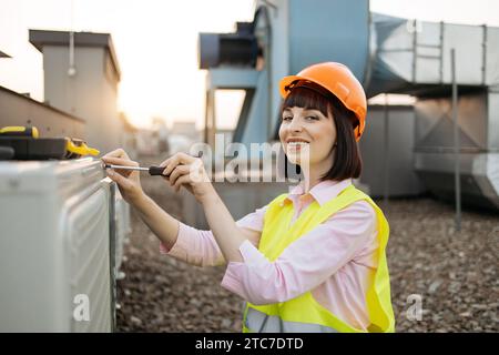 Focused female tightening bolt on cooling system outdoors Stock Photo