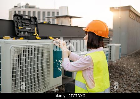 Lady engineer taking screwdriver and fixing cooling system Stock Photo