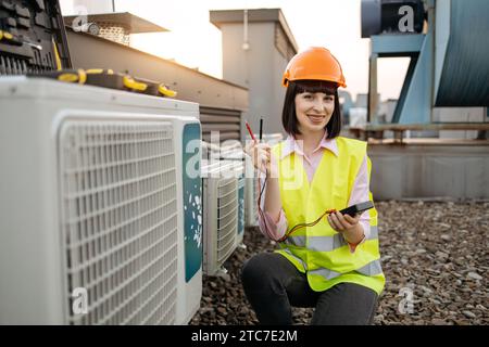 Female measuring voltage with multimeter in air conditioner Stock Photo