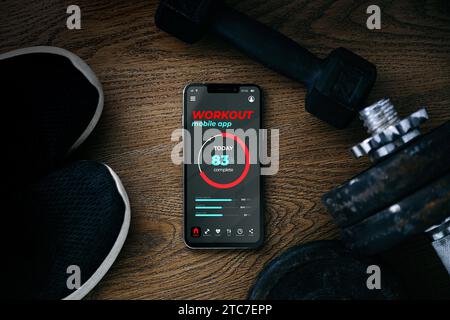 Training application on mobile phone screen. Top view of fitness dumbbells, sneakers and a smartphone showing a health and workout app. Concept of wel Stock Photo