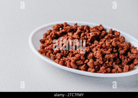 some fried mock ground meat in an oval white ceramic dish placed on a pale gray surface Stock Photo