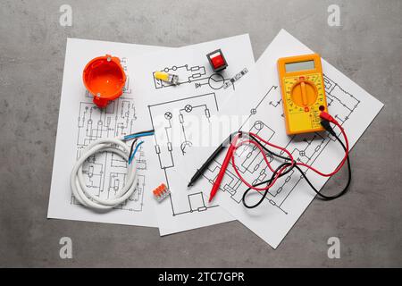 Wiring diagrams, digital multimeter and other electrician's equipment on grey table, flat lay Stock Photo