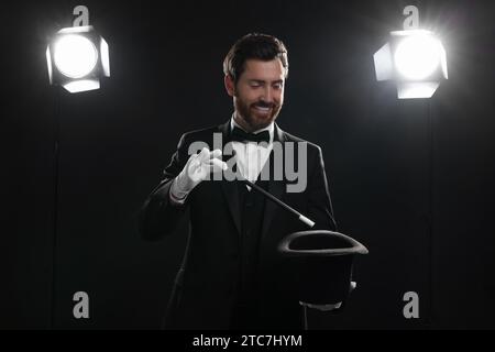 Happy magician showing magic trick with top hat on stage Stock Photo