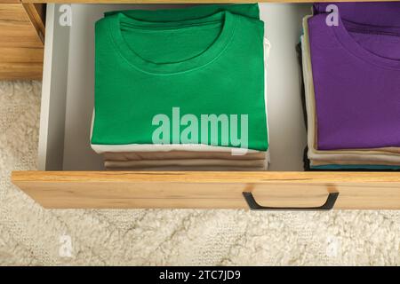 Stacks of different folded shirts in drawer indoors, top view. Organizing clothes Stock Photo