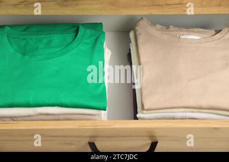 Stacks of different folded shirts in drawer. Organizing clothes Stock Photo