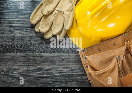 Leather tool belt safety gloves building helmet on black board Stock Photo