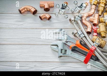 Copper and brass plumbing fittings for connection pipes and adjustable wrenches on vintage wooden boards Stock Photo