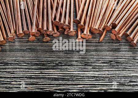 Heap of copper nails on wooden board Stock Photo