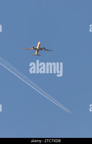 Singapore Airlines A350-941, reg 9V-SJB at low altitude approaching Manchester Airport at golden hour with another aircraft's contrail in the distance Stock Photo