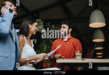 Diverse team of professionals discussing blueprint details and project costs at a coffee bar. Successful cooperation in urban planning. Stock Photo