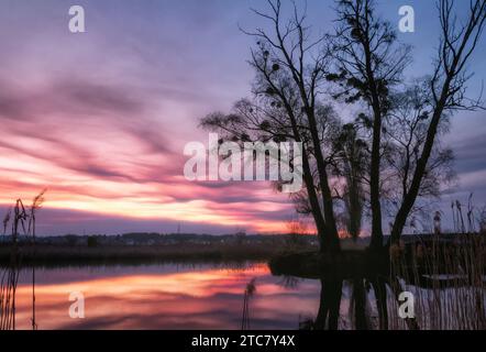 Dramatic landscape with beautiful glowing sky with clouds over a lake at sunset. Beauty of nature's colors during the golden hour. Stock Photo