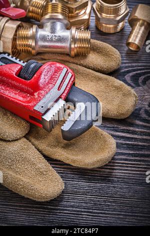 Leather protective gloves monkey wrench brass plumbing fittings ball valve on wooden board Stock Photo