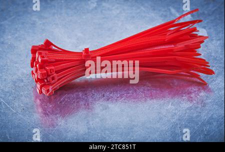 Red plastic self-locking cable ties on metallic background construction concept Stock Photo