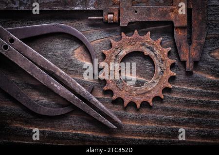 Rusted antique measuring calipers with cog- wheel on vintage dark wooden background close up view construction concept Stock Photo