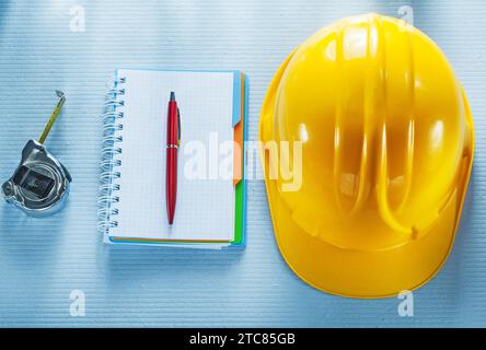 Checked notebook pen hard hat tape measure Stock Photo