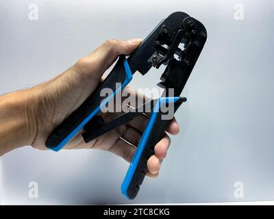Hand holding Lan RJ45 3in1 Crimping Tool Pliers on white background Stock Photo