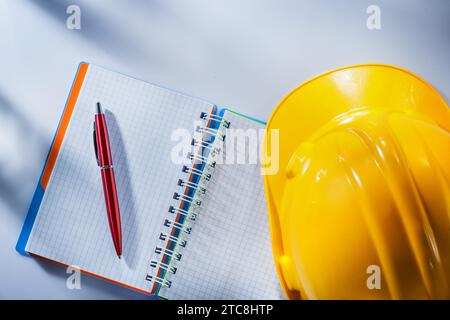 Hard hat checked notepad pen on white background Stock Photo