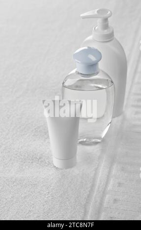Two bottles and tube on white towel Stock Photo
