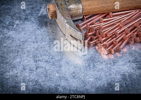 Copper construction nails vintage claw hammer on metallic background Stock Photo