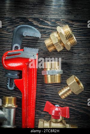 Plumbing adjustable wrench threaded pipe fittings water valve on wooden board Stock Photo