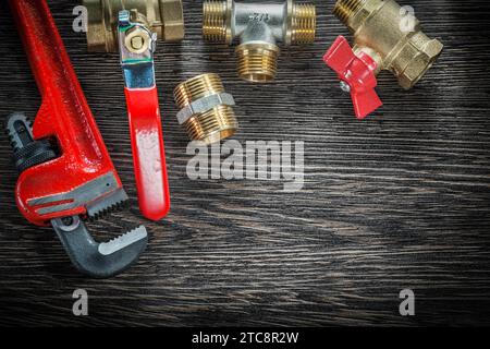 Plumbing monkey wrench pipe fittings water valve on vintage wooden board Stock Photo