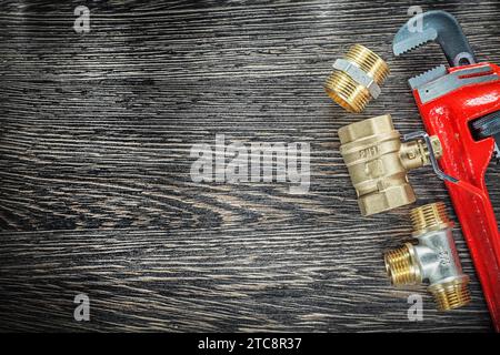 Plumbing monkey wrench pipe connectors on vintage wooden board Stock Photo