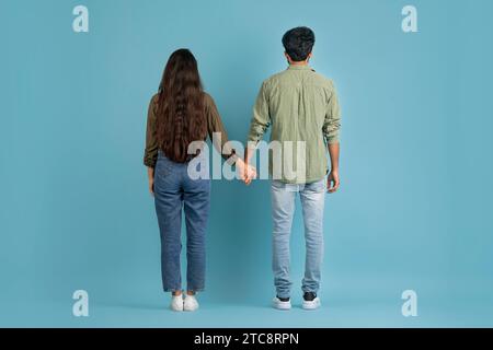 Back view of millennial couple posing on blue background Stock Photo