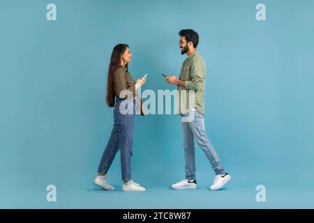 Side view young indian couple using smartphones and walking Stock Photo